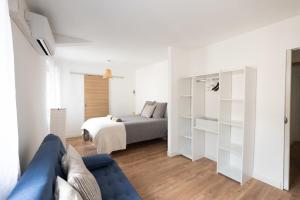 a white bedroom with a bed and a blue couch at Bardelours 1 Charming house with swimming pool in the heart of the Pic Sa in Saint-Bauzille-de-Montmel +24 photos