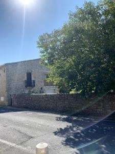 a building with a stone wall and a tree at Bardelours 2 Charming apartment with terrace in the heart of the villag in Saint-Bauzille-de-Montmel +10 photos
