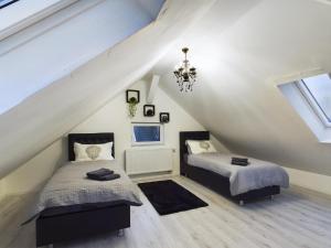 a attic bedroom with two beds and a chandelier at Villa am Staderhof in Leichlingen