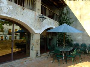 una mesa y sillas con una sombrilla en el patio en Can Ventura, en Sant Feliu de Pallerols