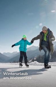 a man and a child are holding hands on the snow at SeeHotel & SeeApartments Kärntnerhof- direkt am See! in Weissensee