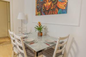 einem Esstisch mit weißen Stühlen und einem Gemälde in der Unterkunft Lakeside Hideaway - Lakefront & Central in Lecco