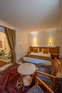 ケルアンにあるDar Dhiafa Paul Klee Kairouanのベッドとテーブルと椅子のあるホテルの部屋