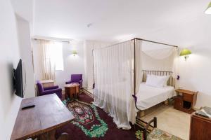 ケルアンにあるDar Dhiafa Paul Klee Kairouanのベッドルーム(天蓋付きベッド1台、テーブル付)