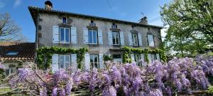 an old house with purple flowers in front of it at Chambres d'hôtes de Massigoux in Aurillac