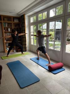 two people doing yoga in a room with mats at Manoir Saint-André,B&B de charme in Theix