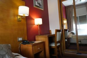een hotelkamer met een bureau en een spiegel bij Hotel coventry in Santiago del Estero