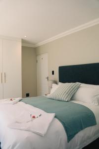 een slaapkamer met een groot wit bed met een blauw hoofdeinde bij Two on Bramble in Hilton