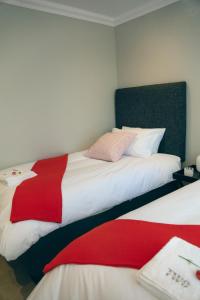 een slaapkamer met twee bedden met rode en witte lakens bij Two on Bramble in Hilton
