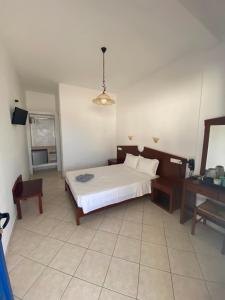 a bedroom with a large white bed and a desk at Elpis Rooms in Mylopotas