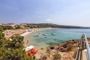 a beach with people and boats in the water at Veranda Vista Mare Isola Rossa in Isola Rossa