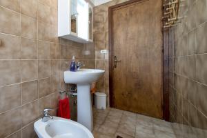 a bathroom with a sink and a wooden door at Veranda Vista Mare Isola Rossa in Isola Rossa +11 photos
