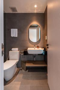 een badkamer met een wastafel, een toilet en een spiegel bij COMMON INN Thu Dau Mot in Ga Phú Văn