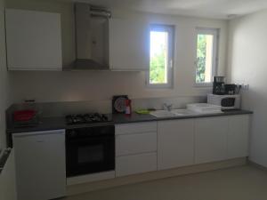 a kitchen with white cabinets and a stove and a sink at Gite Le Logis Dauphinois in Roussillon en Isere