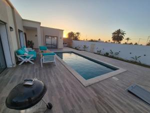 a backyard with a pool and a table and chairs at Villa Midoun in Midoun