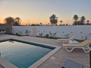 a swimming pool with two chairs next to a fence at Villa Tezdaine in Midoun