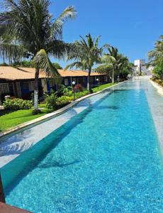 ein großer Pool mit blauem Wasser und Palmen in der Unterkunft Casa de Férias no Sôssego in Itamaracá