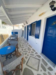 a patio with blue doors and tables and chairs at Elpis Rooms in Mylopotas