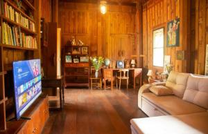 a living room with a couch and a tv at Teak House Homestay I in Ban Thung Satong