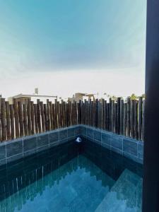 a swimming pool in front of a wooden fence at MHV Milagres - Studio Guadalupe 11 in Passo de Camarajibe