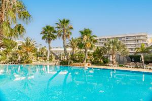 a large swimming pool with palm trees and a building at Alfagar Prestige in Albufeira