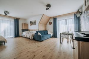 a living room with a blue couch and a bed at Willa Janowa in Bukowina Tatrzańska