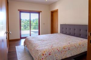 une chambre avec un lit et une porte coulissante en verre dans l'établissement Casa Oliveira e Quinteiro Gerês, à Gerês