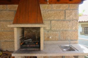 - une cuisine en pierre avec une cuisinière et un évier dans l'établissement Casa Oliveira e Quinteiro Gerês, à Gerês