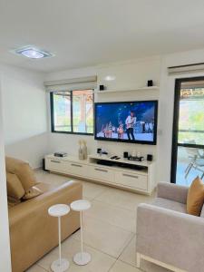 a living room with a large flat screen tv at Flat espaçoso e confortavel no hotel Canarius Gravata in Gravatá