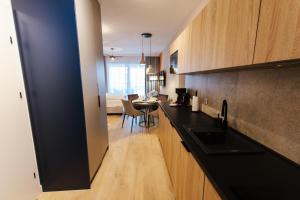 a kitchen with a black counter top and a table at VacationClub - Baltic Waves Resort Apartament A109 in Międzyzdroje
