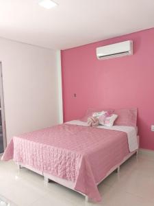 a pink bedroom with a bed with a pink wall at Family Space - Chacara Rosa Beautiful and Comfortable in Cuiabá