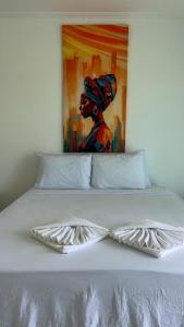 a white bed with a painting of a woman at Mambo beach gamboa in Cayru