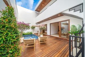 een overdekt terras met een zwembad, stoelen en planten bij Walk to the Beach from This Brand New 3BR Villa with Pool! in Sanur