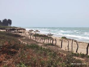 a beach with a fence and the ocean at Baobab Beach Villa in Abene