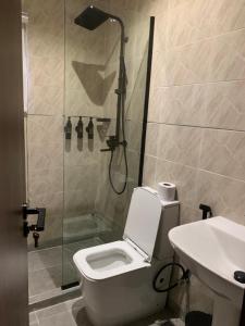 um banheiro com chuveiro, vaso sanitário e pia em Five Clover Hotel, Ilupeju em Lagos