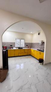 诺伊达Banke bihari farm的一个宽敞的厨房，配有黄色橱柜和一个拱门。