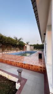 诺伊达Banke bihari farm的房子里有一个带砖砌露台的游泳池