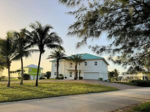 Casa blanca con techo azul y palmeras en Escape to Paradise In West End Old Bahama Bay, en West End