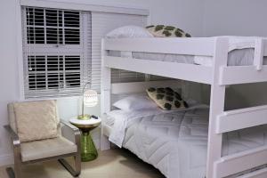 1 dormitorio con litera blanca y silla en Escape to Paradise In West End Old Bahama Bay, en West End