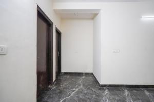an empty corridor with white walls and a black door at Hotel O Royal residency in Dera Māndi +37 photos