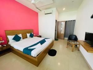 a bedroom with a bed and a desk and a television at Hamlet Beach Villas Alleppey in Alleppey