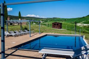 a swimming pool with chairs and a table and a hill at Podere Fossaccio Casa Biancospino in Asciano