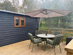 ein Tisch und Stühle mit einem Sonnenschirm auf einem Deck in der Unterkunft Martins Meadow Private Wellness Escape in Ballynahinch