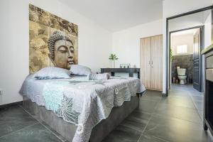 ein Schlafzimmer mit einem Bett, an dem ein Kopf als Wandgemälde prangt in der Unterkunft Villa Caudy Kaz - calme et confort - Wiskeys in Sainte-Marie