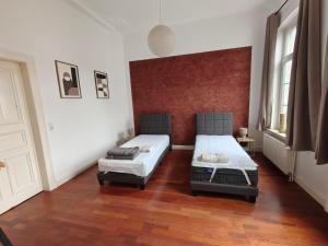 deux lits dans une chambre avec parquet dans l'établissement Schiefe Stadtvilla Oldenburg - großes Altbauhaus, à Oldenbourg