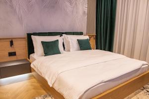 - une chambre dotée d'un grand lit avec des oreillers verts et blancs dans l'établissement Luxurious apartment by Hotel Casa David 2025, à Craiova