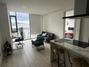 キトにあるSuite Piso 17 - Increible Vista - Agua filtrada ilimitadaのキッチン、ベッドルーム1室の景色を望むリビングルーム