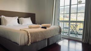 ein Schlafzimmer mit einem großen Bett und einem großen Fenster in der Unterkunft Maribel's Place in Funchal