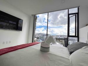 キトにあるSuite Piso 17 - Increible Vista - Agua filtrada ilimitadaのベッドと大きな窓のある寝室