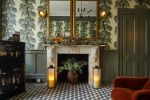 een woonkamer met een open haard met kaarsen en een spiegel bij Georgian House Hotel in Londen
